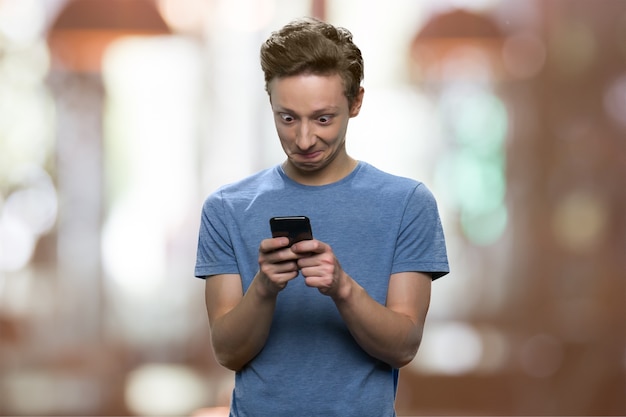 Openedeyed teen boy is looking at his smartphone