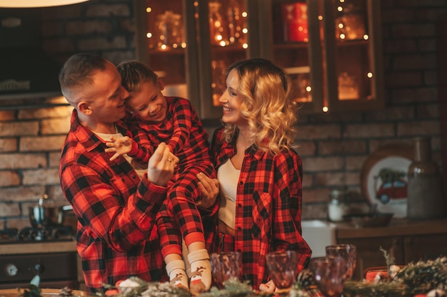 Openhartige authentieke schattige gelukkige familie in rode geruite pyjama brengt tijd samen door in lodge Xmas versierd