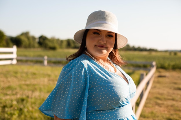 Openhartige vrouw met hoed op landbouwgrond geniet van de zomer
