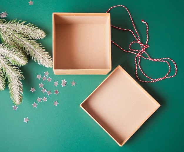 Opening and empty Christmas gift box on the green background with pine branch and Christmas decoration