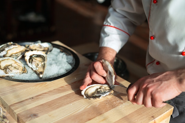 Apertura delle ostriche vuote e piatte. lo chef apre le ostriche nel ristorante.