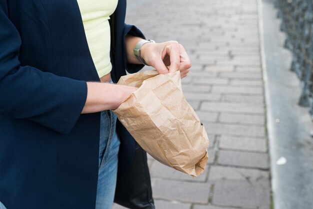 Photo opening paper bag on city sidewalk