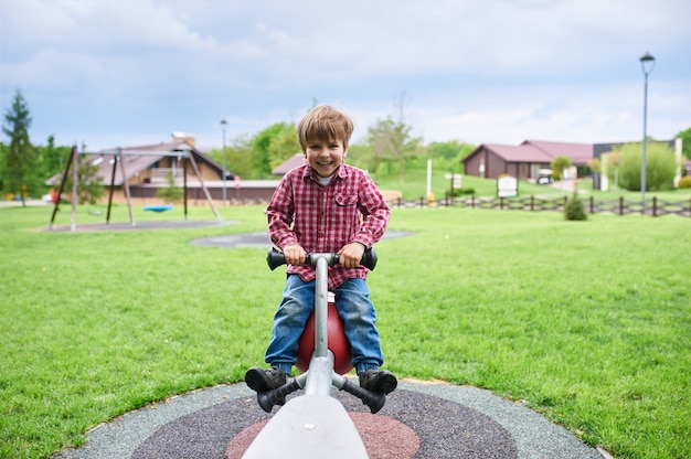 Openlucht portret van schattige peuter lachende jongen swingend op een schommel op de speelplaats