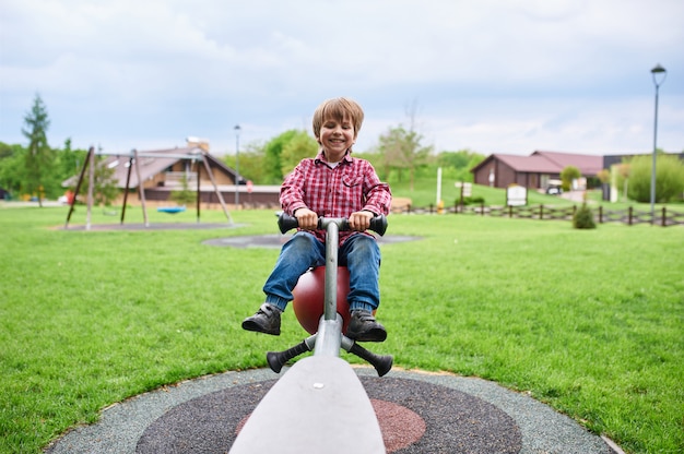 Openlucht portret van schattige peuter lachende jongen swingend op een schommel op de speelplaats