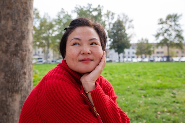 Openluchtportret van een Chinese dame van middelbare leeftijd die in het openbare park zit