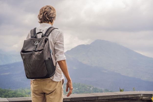 Openluchtportret van een jonge man die 's ochtends op de Batur-vulkaan en Agung-berguitzicht kijkt vanuit Kintamani Bali Indonesia