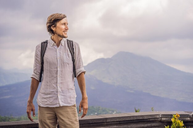 Openluchtportret van een jonge man die 's ochtends op de Batur-vulkaan en Agung-berguitzicht kijkt vanuit Kintamani Bali Indonesia