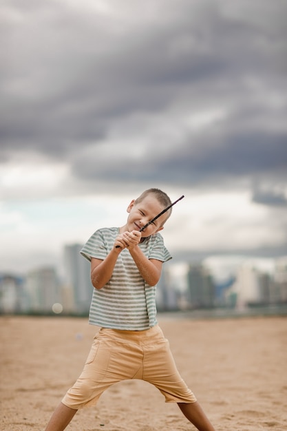 Foto openluchtportret van een kleine leuke jongen met stok