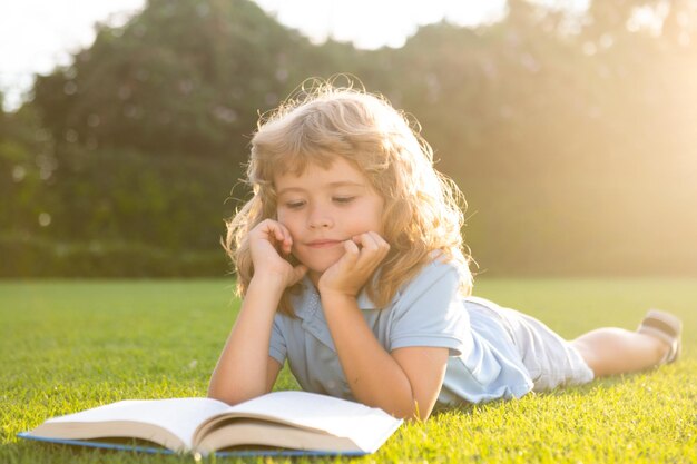 Openluchtportret van een schattige jonge kleine jongen die een boek leest terug naar het onderwijs van schoolkinderen, begin o