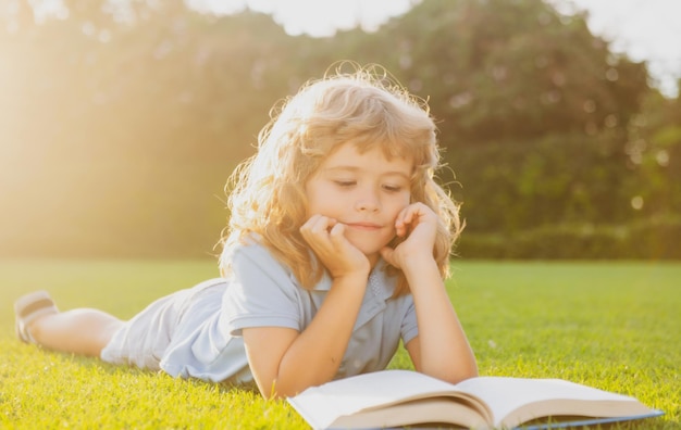 Openluchtportret van een schattige jonge kleine jongen die een boek leest terug naar het onderwijs van schoolkinderen, begin o