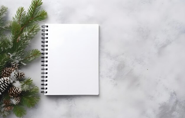 openned empty notebook and christmas tree branch on grey snowy background top view