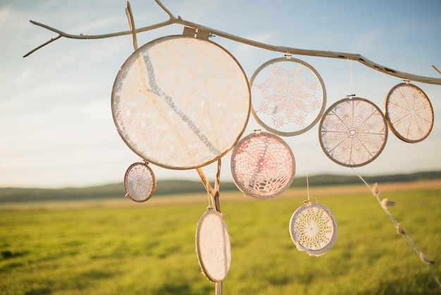 Openwork dream catchers hang on a wooden arch in nature