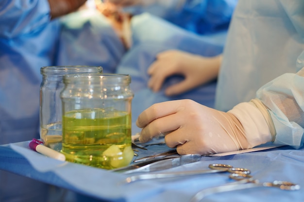 The operating room nurse's hand rests on the instrument table