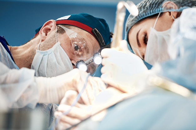 Vista dell'operazione da un paziente, una squadra di medici vista dal basso che esegue l'operazione in attrezzature moderne, dispositivi di illuminazione sulla testa.