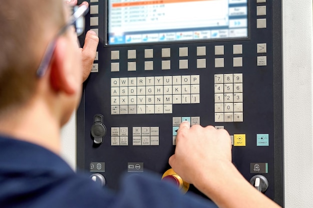 Оператор CNC-мельницы пишет программу и вносит корректировки для обработки деталей путем резки
