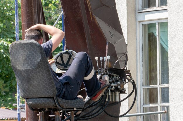 The operator driver sits in the open cabin of the tower crane\
behind the control levers of the hydraulic drive of various systems\
control panel levers for lifting operation of mobile crane\
truck