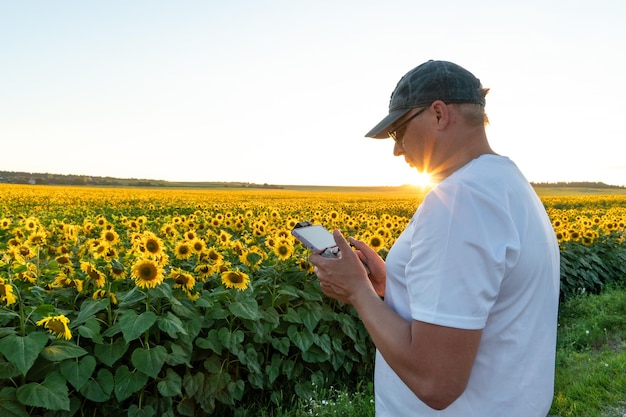 The operator holds the remote control of the drone in his hands\
a farmer uses a quadcopter to work at an industrial facility remote\
with smartphone in hands agriculture modern business concept