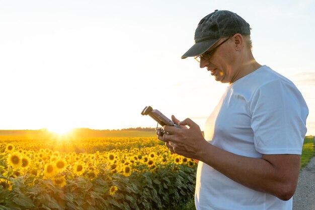 The operator holds the remote control of the drone in his hands A farmer uses a quadcopter to work at an industrial facility Remote with smartphone in hands agriculture modern business concept