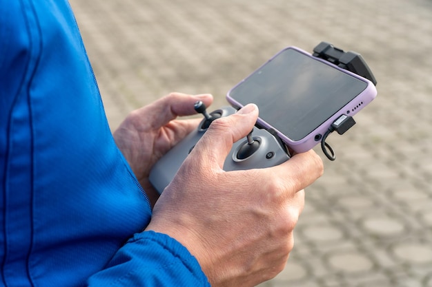 The operator holds the remote control of the drone in his hands A farmer uses a quadcopter to work at an industrial facility Remote with smartphone in hands agriculture modern business concept