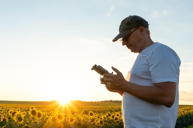 운영자는 드론의 원격 제어를 손에 들고 있습니다. 농부는 쿼드콥터를 사용하여 산업 시설에서 일합니다. 손에 스마트폰을 들고 있는 원격 농업 현대 비즈니스 개념