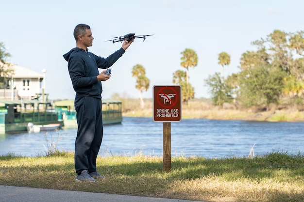 Operator is preparing to fly his quadcopter in national park no drone area Man unlawfully using his UAV near restriction notice sign