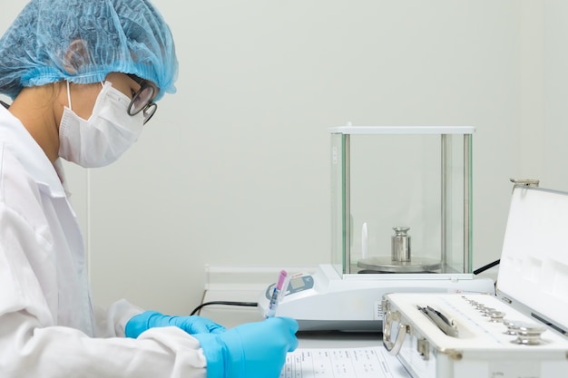 Operator is recording the data of analytical balance calibration work.