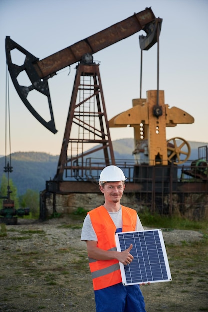 Operator with solar panel on the backdrop of pump jack