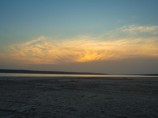 Opgedroogd zandig estuarium onder de grenzeloze hemel Schemering op het strand van het zoutmeer