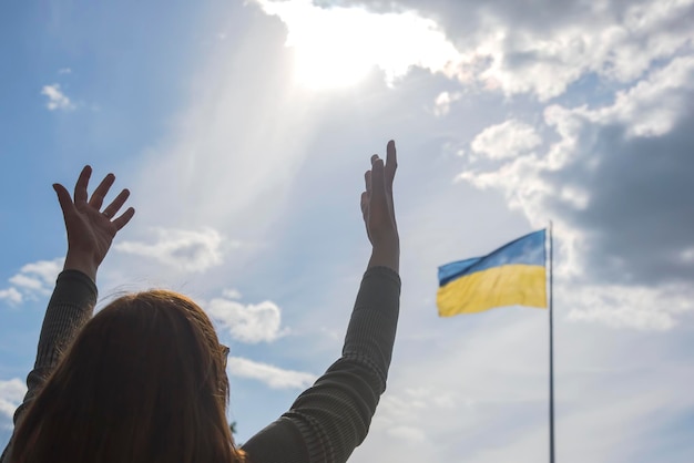 Opgeheven handen naar de hemel tegen de achtergrond van de vlag van Oekraïne Gebed om hulp en