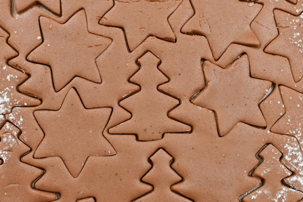 Opgerold gekruid deeg gesneden in blikken Achtergrond Kerstmis winter nieuwjaar Firtrees sterren meel Bovenaanzicht close-up