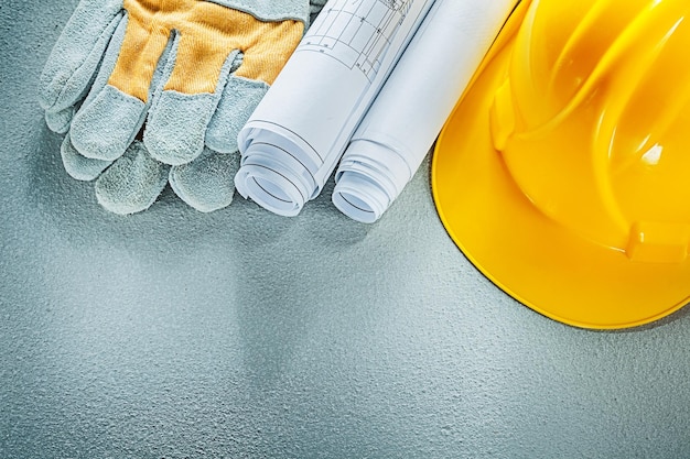 Opgerolde blauwdrukken veiligheidshandschoenen op betonnen ondergrond
