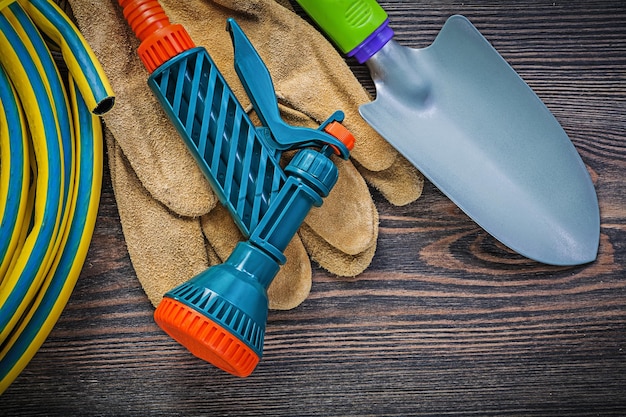 Foto opgerolde tuin rubberen slang beschermende handschoenen hand schop op houten plank tuinieren concept