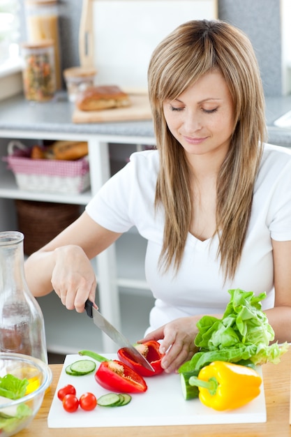 Opgetogen vrouw die een maaltijd in de keuken voorbereidt