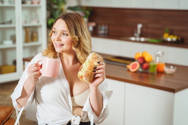 Opgetogen vrouw die positiviteit uitdrukt terwijl ze thuis luncht