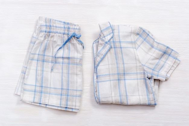 Opgevouwen warmwitte pyjama met blauwe ruiten of strepen op wit hout