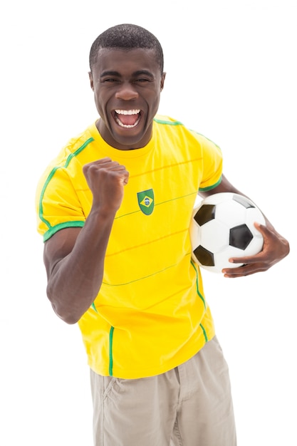 Opgewekte Braziliaanse voetbalventilator die holdingsbal toejuichen