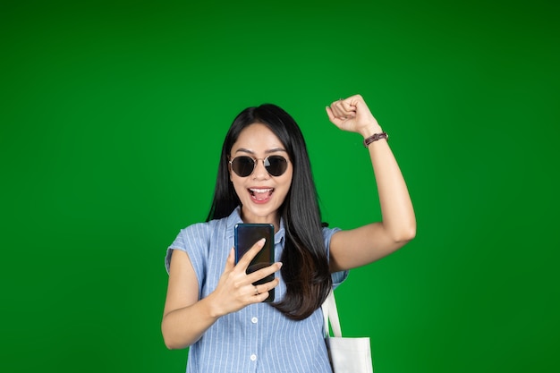 Opgewonden Aziatische vrouw tijdens het gebruik van een mobiele telefoon
