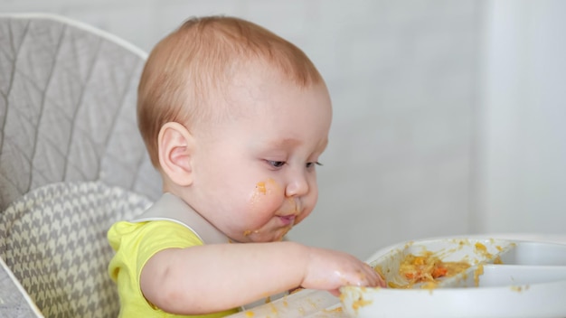 Opgewonden babymeisje raakt etensresten op bord aan en proeft