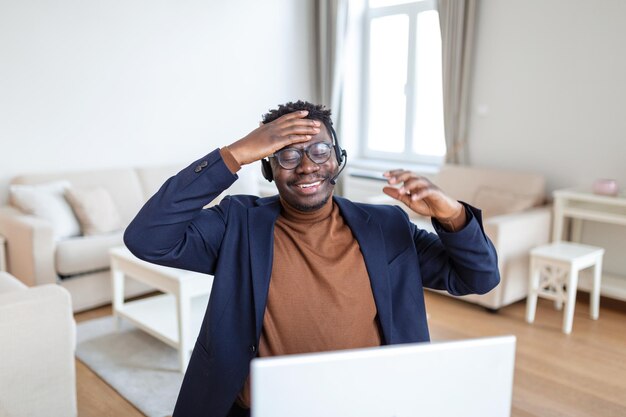 Opgewonden biracial mannelijke callcenteragent in headset veel plezier lachen werken op computer online dolblij Afro-Amerikaanse man bezig met studeren of kijken naar grappige trainingswebinar op computergadget