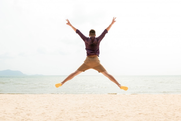 Opgewonden energieke gelukkig man springen op het strand