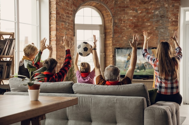 Opgewonden, gelukkig groot familieteam kijken samen naar sportwedstrijd thuis op de bank