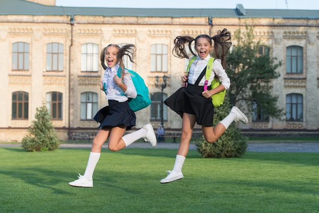 Opgewonden gelukkige meisjes schooluniform rennen, schiet op concept.