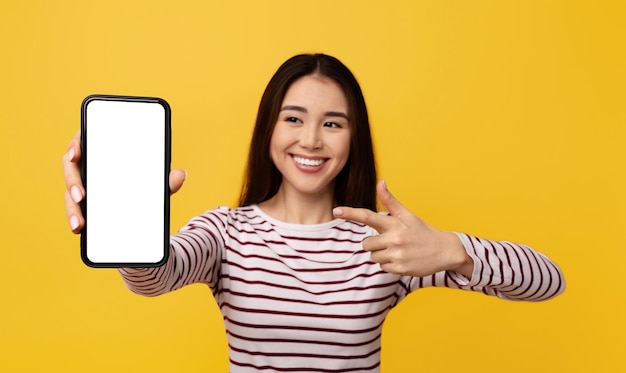 Opgewonden jonge Aziatische vrouw die telefoon toont met mockup