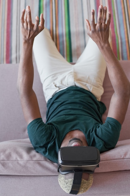 Opgewonden jonge man in virtual reality-headset die thuis een videogame speelt en zichzelf thuis probeert te vermaken