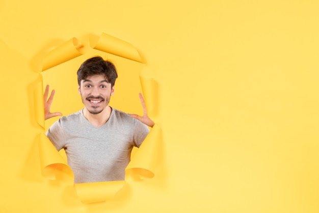 opgewonden jonge man op gescheurde gele papieren achtergrond indoor gezichtsman