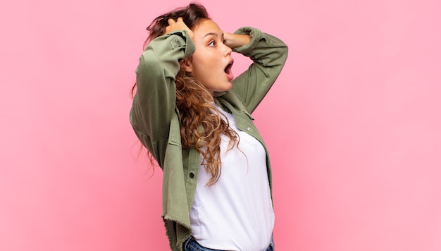 Opgewonden jonge mooie vrouw op roze achtergrond