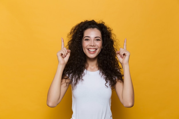 Opgewonden jonge schattige vrouw poseren geïsoleerd op gele wijzen.