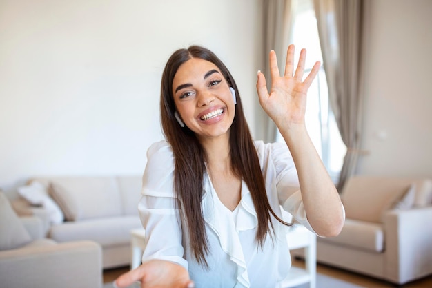 Opgewonden jonge vrouw die naar de camera kijkt en een grappig gesprek voert met collega's online webcamweergave Hoofdschot van een jonge vrouw met een koptelefoon die lacht en plezier heeft vanuit het kantoor aan huis