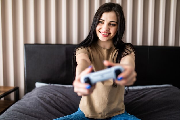 Opgewonden jonge vrouw gamer met gamepad joystick controller spelen videogame zittend op de bank thuis.