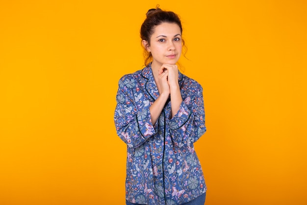 Opgewonden jonge vrouw in blauwe huiskleding, breed glimlachend plezier. Geïsoleerd op gele muur.